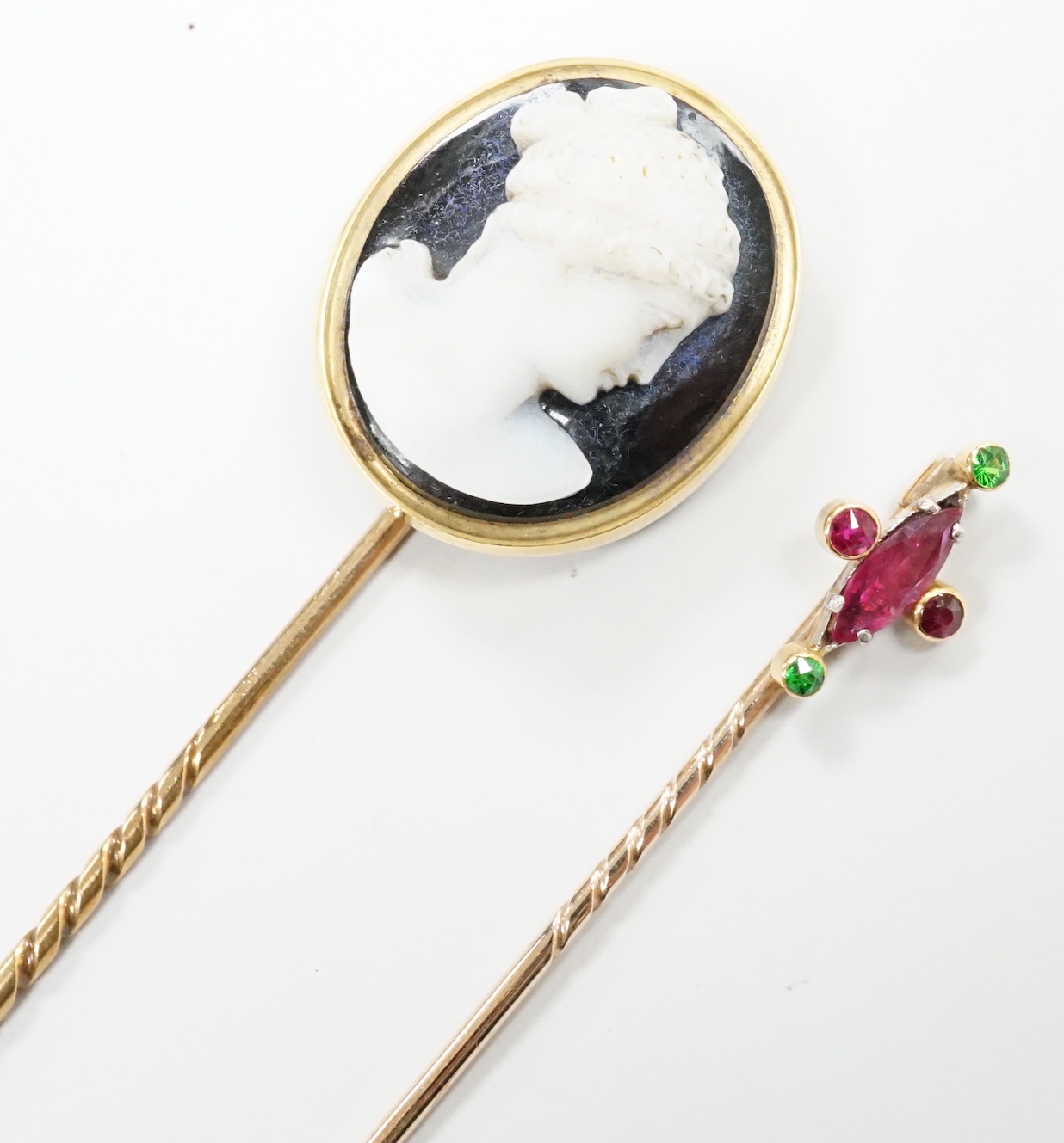 A yellow metal and sardonyx cameo stick pin, 91mm and one other gem set stick pin.